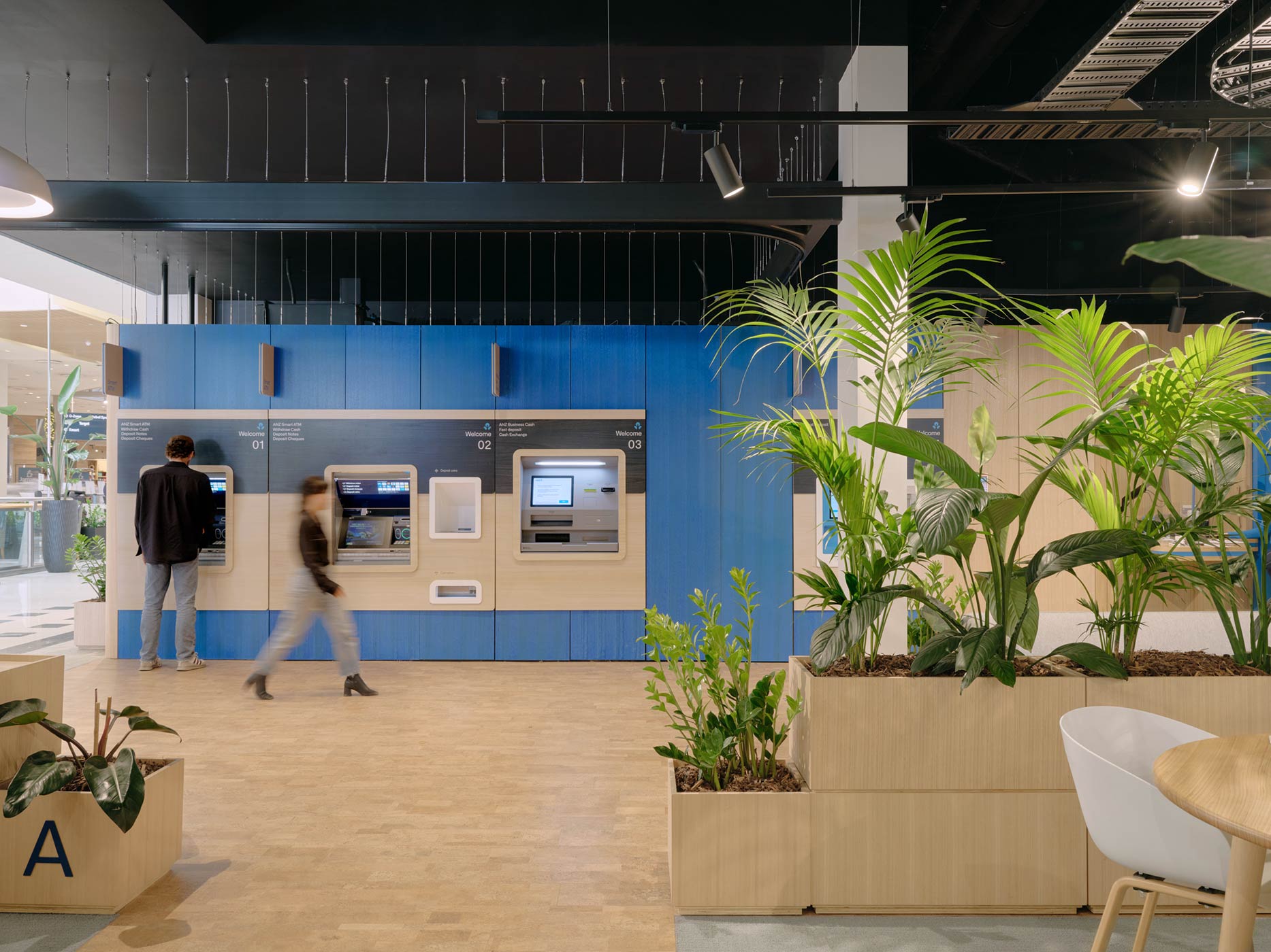 View of ATMs with greenery and seating in the foreground