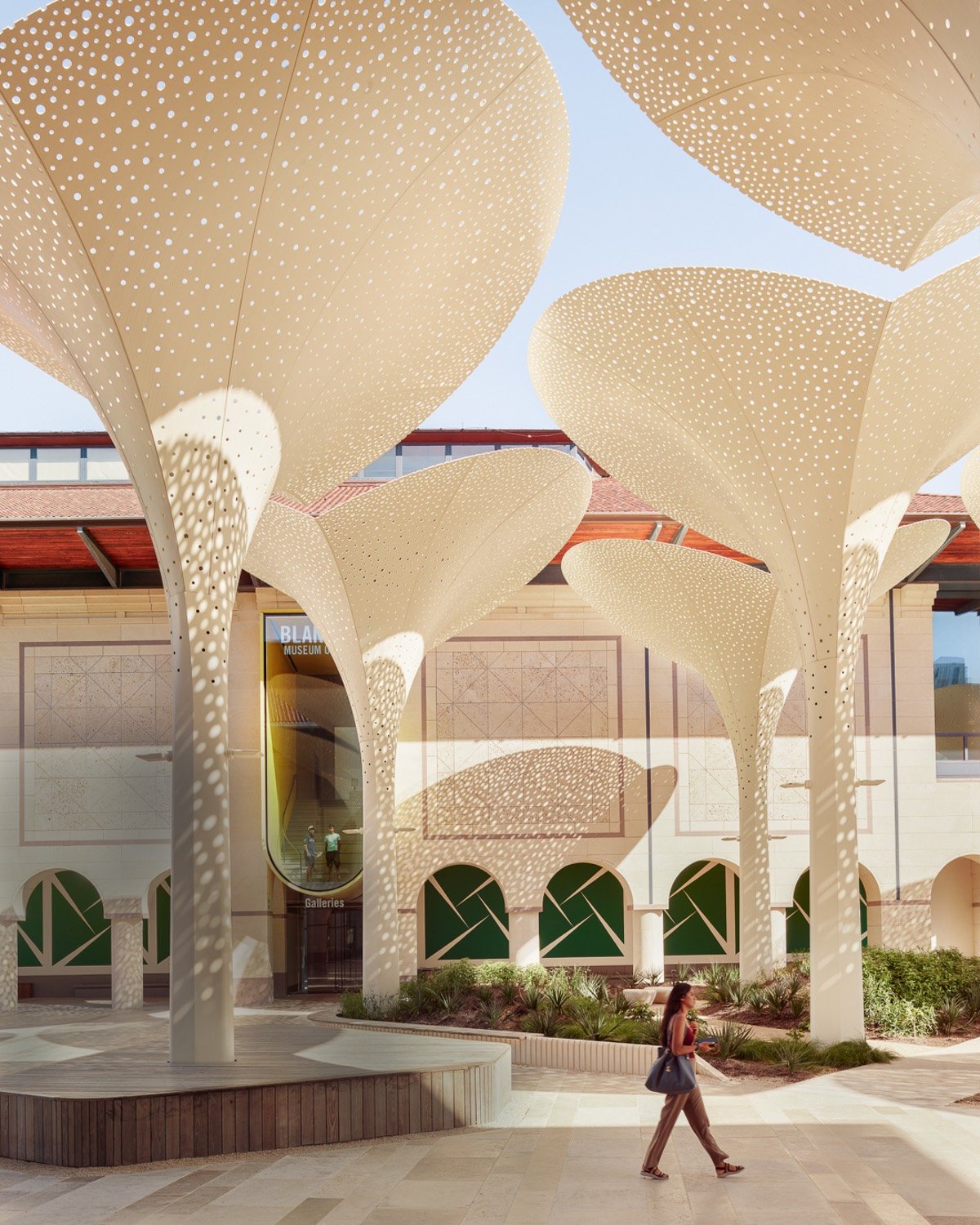 A person walks past a row of tall fibreglass sculptures designed by Snohetta and shaped with folded petal caps outside the Blanton Museum of Art in Austin.