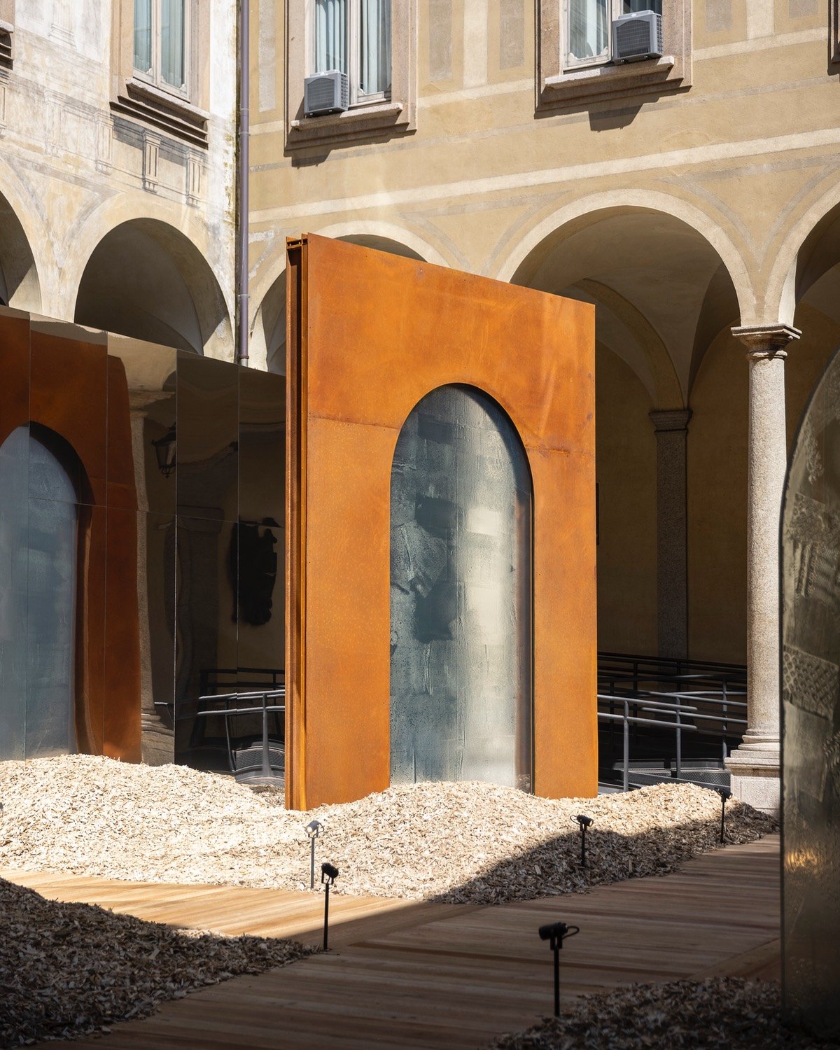 For Milan Design Week 2024, Lasvit presented a series of glass doorways framed in corten steel in a courtyard of a historic palazzo.