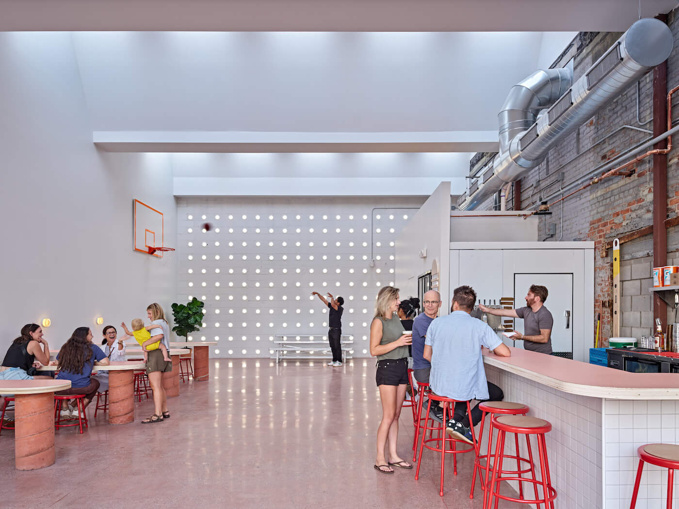 Collect Beer Bar riffs on the site's industrial heritage, with raw, simple finishes and OMA's new sawtooth roof. Image of bar with perforated cinder block wall visible in the background.