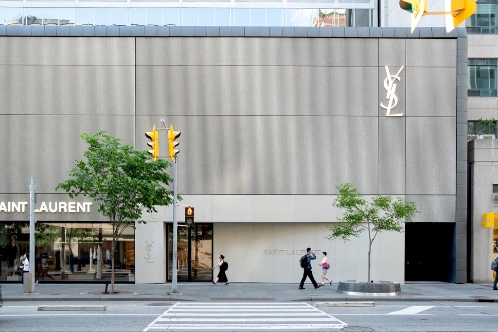 A view of the YSL Saint Laurent store on Bloor Street in Toronto from across the street. The store is covered in concrete panels in the style of brutalist architecture, with the top half featuring a striated texture and the bottom a smoother finish.