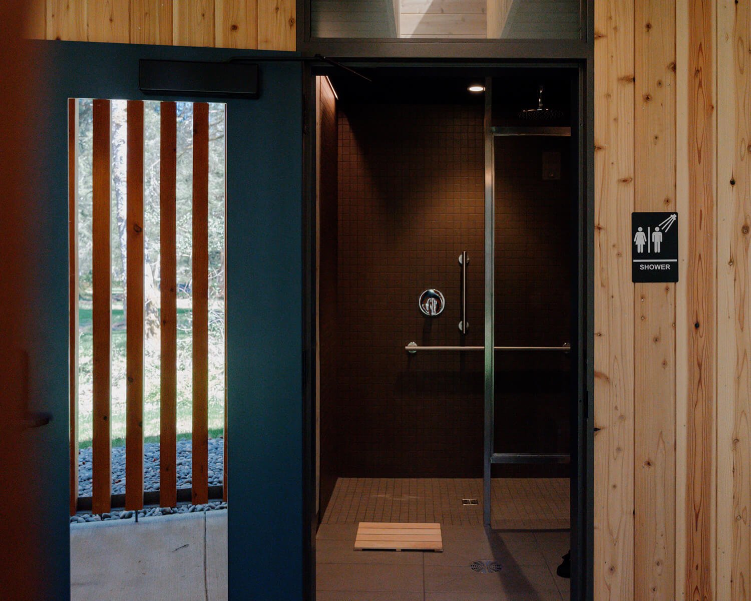 The wash house’s interior features black tiled shower stalls that mirror the exterior palette of Japanese cypress.