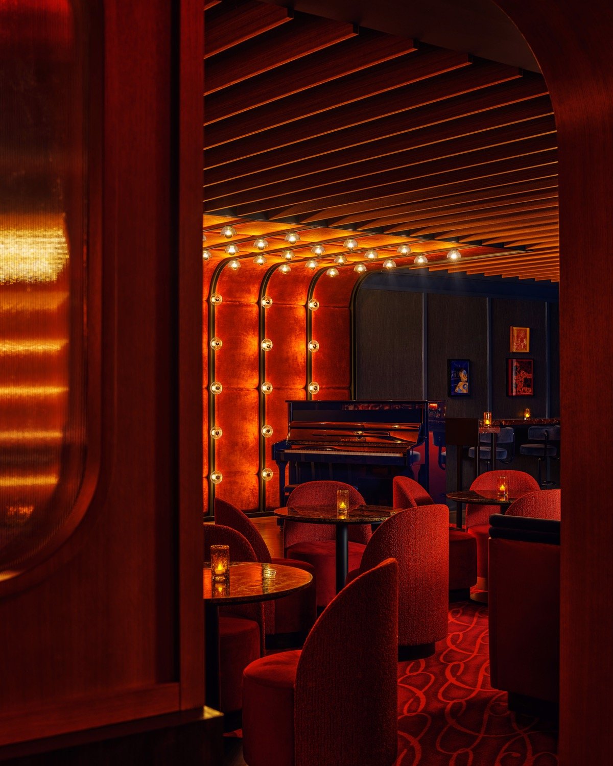 A blue piano sits in the back corner of New York piano bar So&So's surrounded by red velvet chairs.