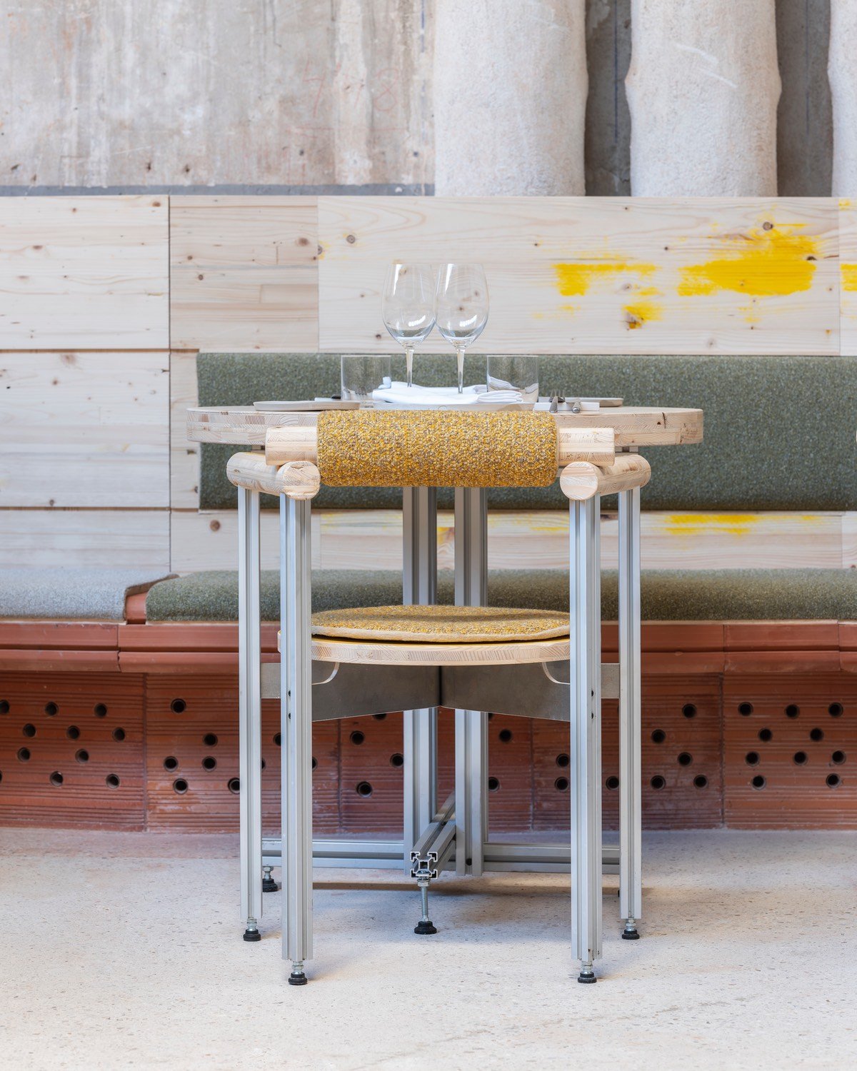 One of the dining chairs at Tramo restaurant in Madrid, built from industrial steel. It sits at a dining table against a partition made from plywood and perforated clay brick modules.