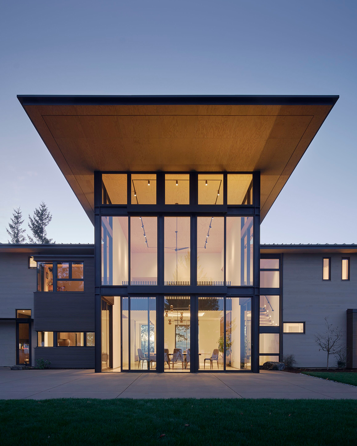 House with double-height glazed wall looking into dining room